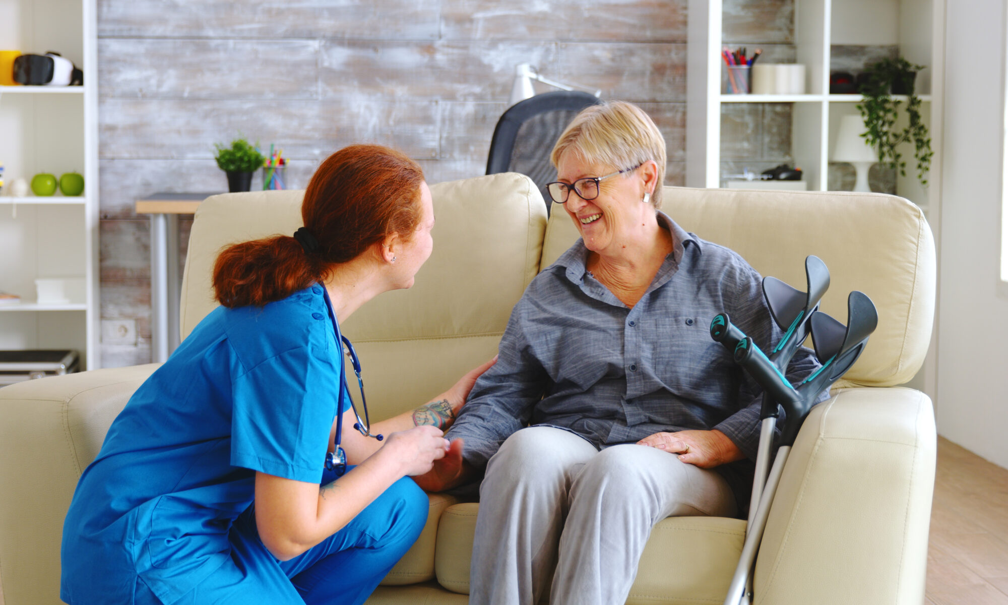 Female nurse talking with old woman with alzheimer in nursing home